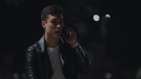 un joven hablando por teléfono por la noche.