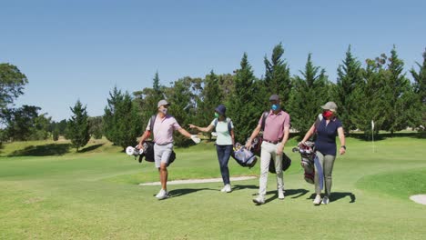 senior people wearing face masks walking with their golf bags at golf course