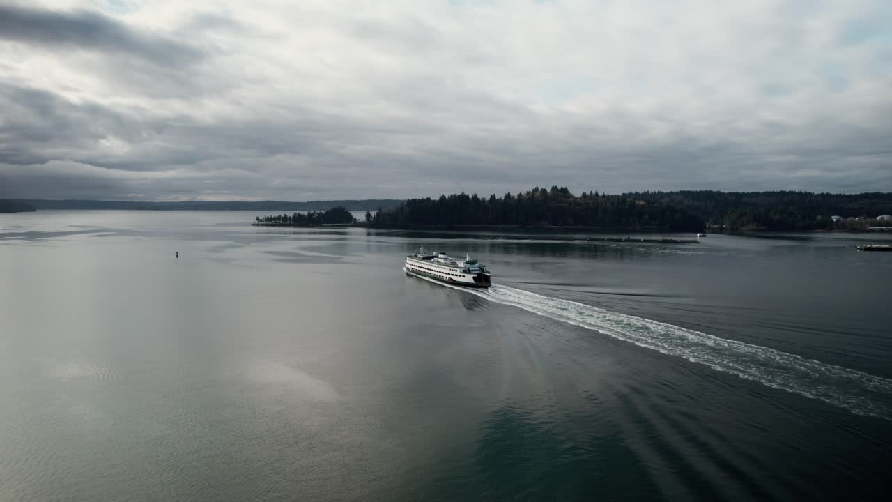 siguiendo detrás de un gran ferry de cercanías en aguas oscuras y tranquilas, las nubes sombrías reflejan, aérea