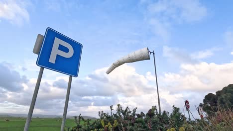 parking sign and wind sock in field