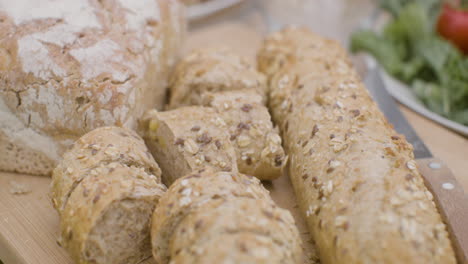 Close-Up-Shot-Of-Fresh-Bread-On-A-Wooden-Board-On-A-Dining-Table-For-An-Outdoor-Party-In-The-Park-1