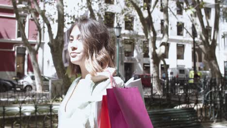 Young-beautiful-woman-holding-bags-on-shoulder-and-walking