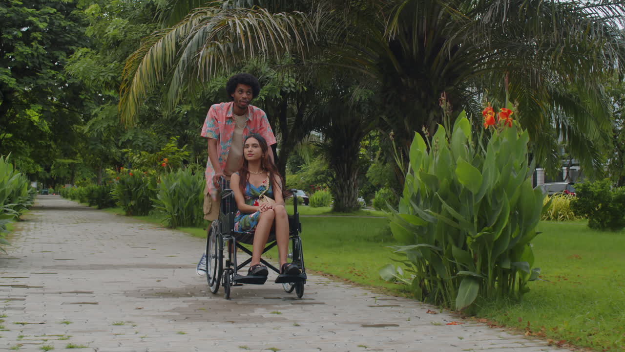 Black Man Pushing Wheelchair of Girlfriend Outdoors