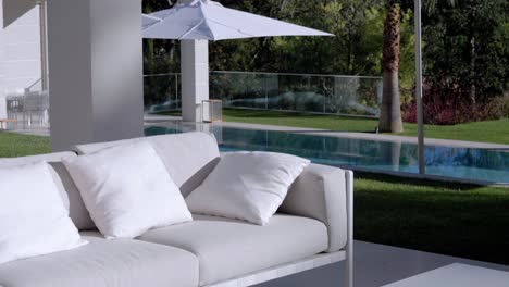 luxurious garden bench with white cushions and magnificent pool in the background