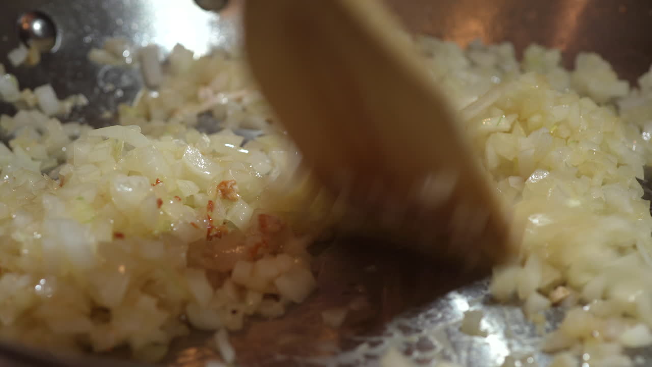 프라이팬에 양파를 볶고 나무 주걱으로 타지 않도록 저어줍니다 - 클로즈업