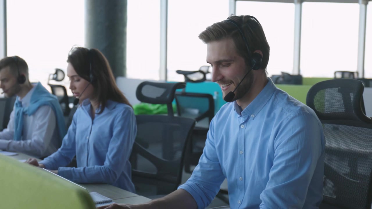 Smilende kundeservicemedarbeidere jobber med headset på et moderne kontor