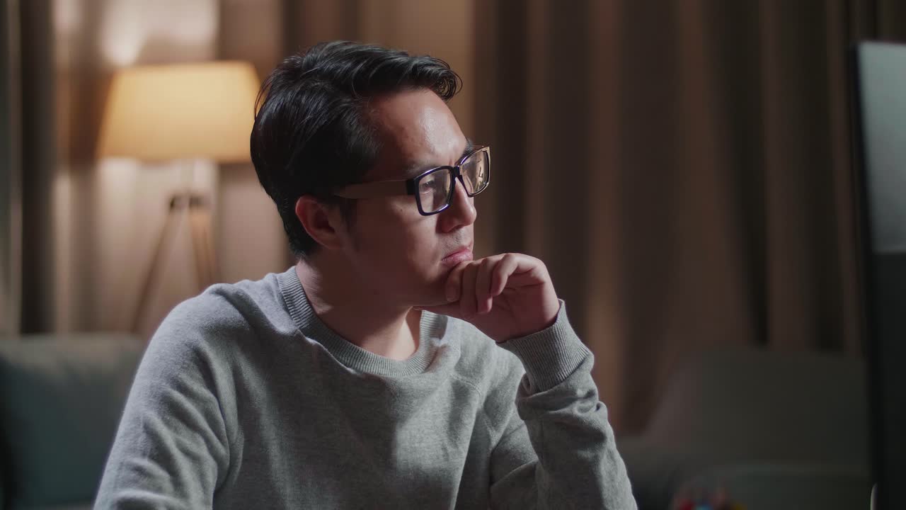 primer plano de un diseñador de calzado masculino asiático pensando mientras trabaja en una computadora de escritorio en casa