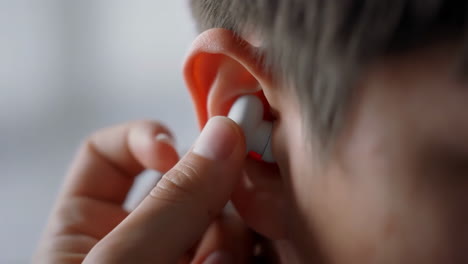 person inserting wireless earbud into ear