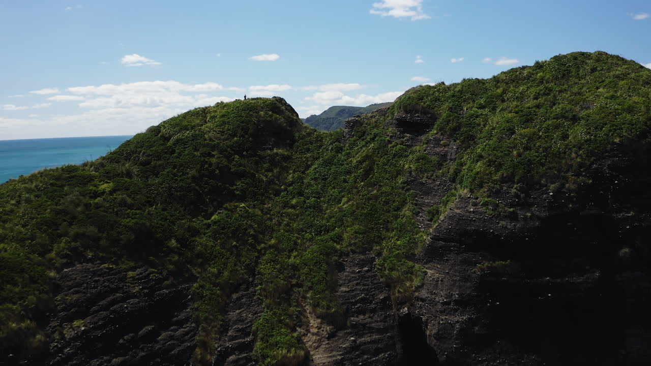 drone disparado sobre un acantilado con vistas al océano turquesa y la costa en la playa de piha, nueva zelanda