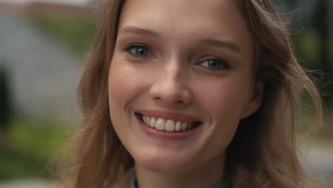 caucasian woman looking at the camera and smiling outdoors.