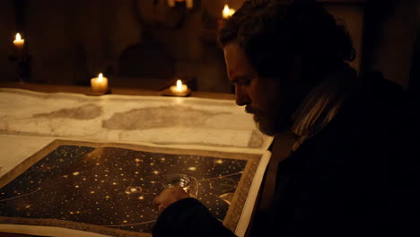man studying a celestial map by candlelight