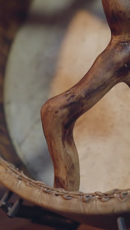 musician with old shamanic drum with handles of curvy sticks in ail cabin macro view. musical instrument for spiritual practices. folk music