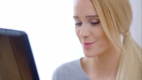 una chica rubia feliz usando su tableta.