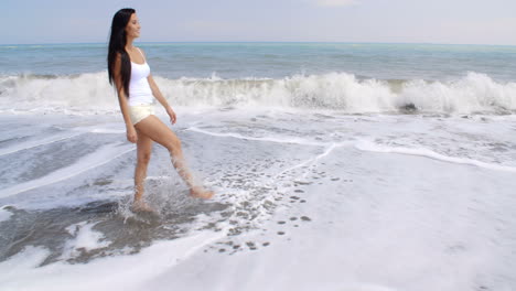 Unbeschwerte-Frau,-Die-Am-Tropischen-Strand-Wasser-Aufwirbelt