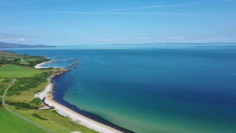 aerial landscape showing the rigged countryside of the scottish highlands, with bright blue sky and turquoise sea