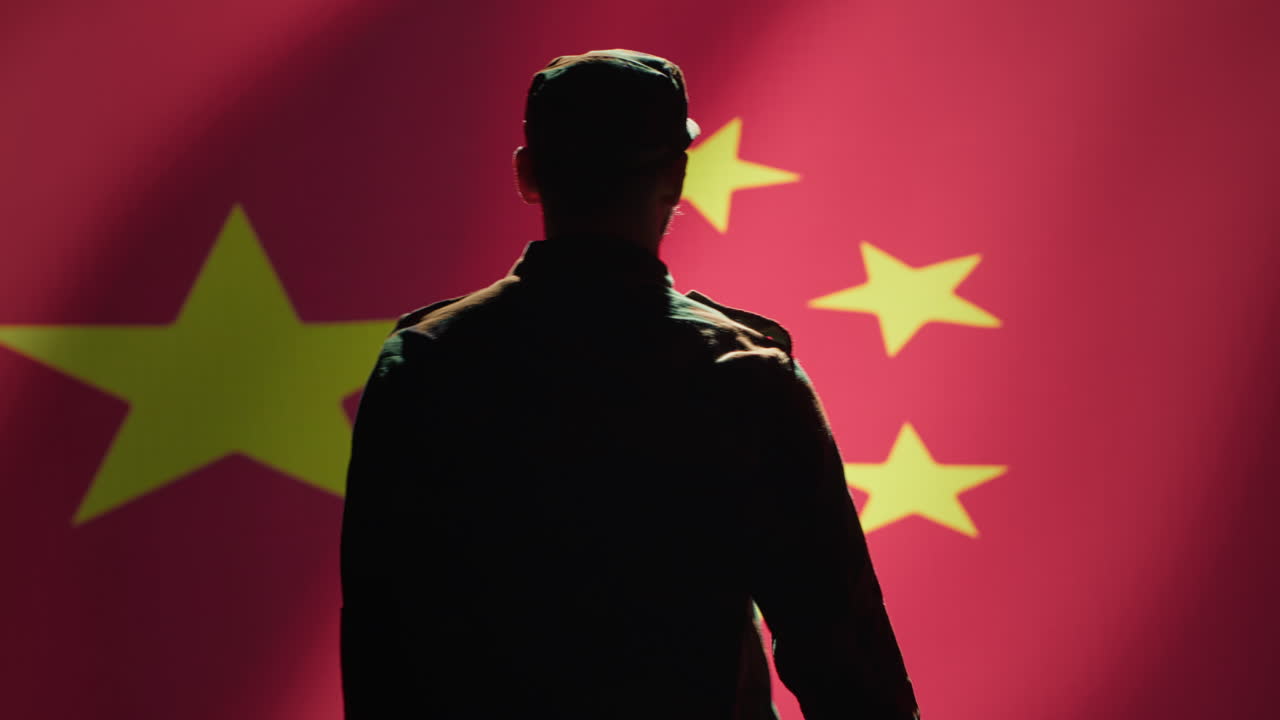 miembro del ejército chino haciendo un gesto de mano de saludo hacia la bandera china