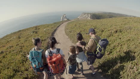 back view of parents and children walking along path towards the sea