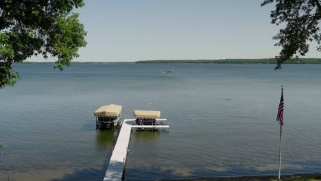 Legen-Sie-Mit-Einem-Ponton-Und-Jetskis-An-Einem-Großen-See-Mit-Einer-Amerikanischen-Flagge-Im-Vordergrund-Und-Einem-Pontonfahren-Im-Hintergrund-An