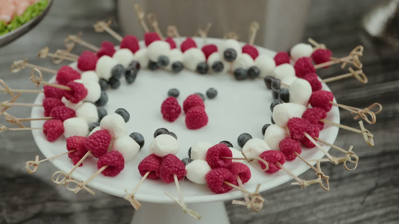 Spiedini di lamponi, mirtilli e mozzarella preparati per un servizio festivo