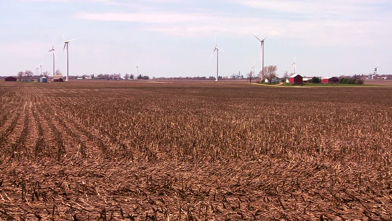 멀리 있는 거대한 풍차는 미국 중서부의 농장 뒤에서 전력을 생산합니다.
