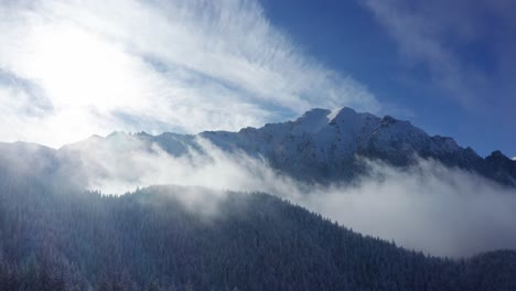 misty bucegi mountains with sunlit peaks and forested slopes, serene nature scene