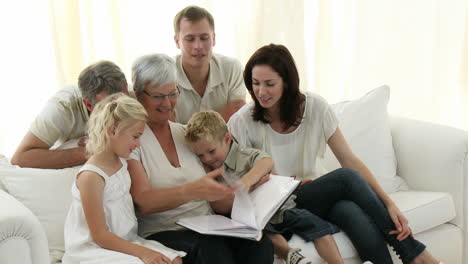 happy family sitting on sofa looking at a photo album at home