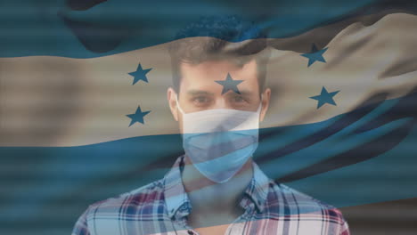 Animation-of-flag-of-honduras-waving-over-man-wearing-face-mask-during-covid-19-pandemic