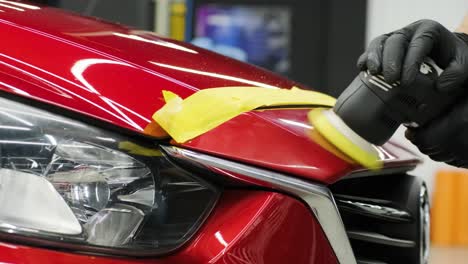 worker polish a red car. car detailing - men are using machinery car polishers maintenance to remove marks repair according to the surface of the car's paint before contin