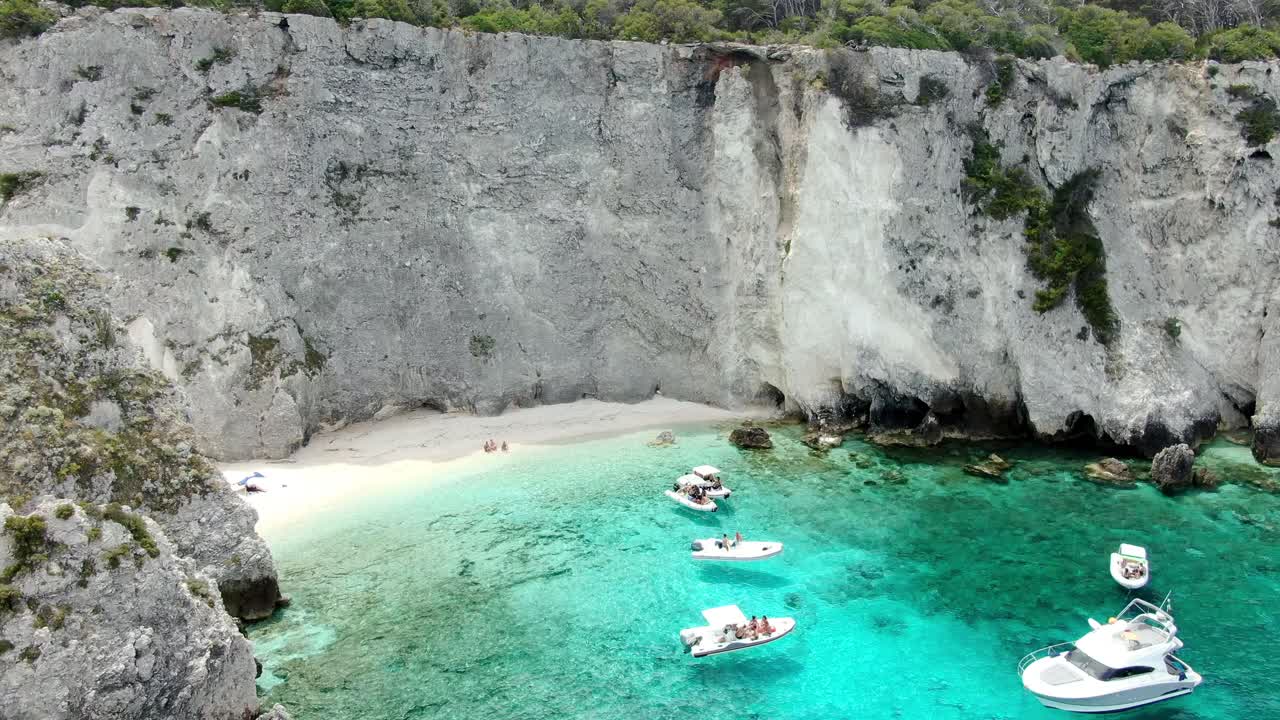 여러 개의 보트와 요트가 있는 이탈리아 트레미티 섬 해변의 영화적 회전 샷이 크리스탈 푸른 바다에서 항해하고 있습니다.