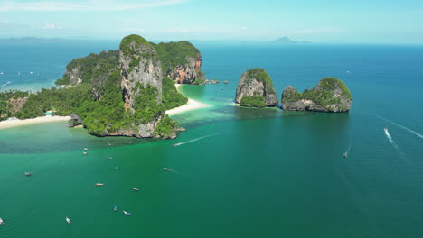 Aerial-view-of-paradise-beach-in-Thailand-Railay-or-Rai-Leh-peninsula-Krabi,-drone-approaching-lonely-tropical-sand-beach-with-sailboat-moored-at-bay-enjoying-holiday