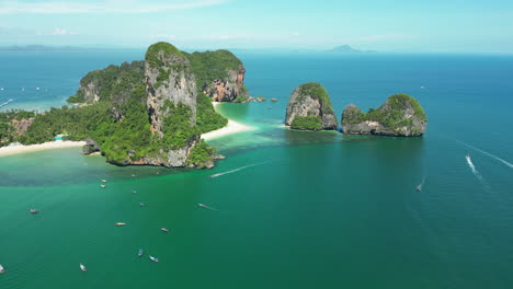 aerial view of paradise beach in thailand railay or rai leh peninsula krabi, drone approaching lonely tropical sand beach with sailboat moored at bay enjoying holiday