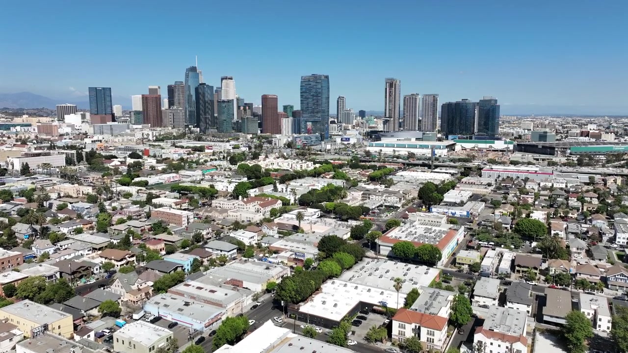 Los Angeles, California, USA: Ampio filmato aereo che mostra gli imponenti grattacieli del centro di Los Angeles sopra un vasto quartiere metropolitano accanto all'autostrada 110. Edifici a molti piani