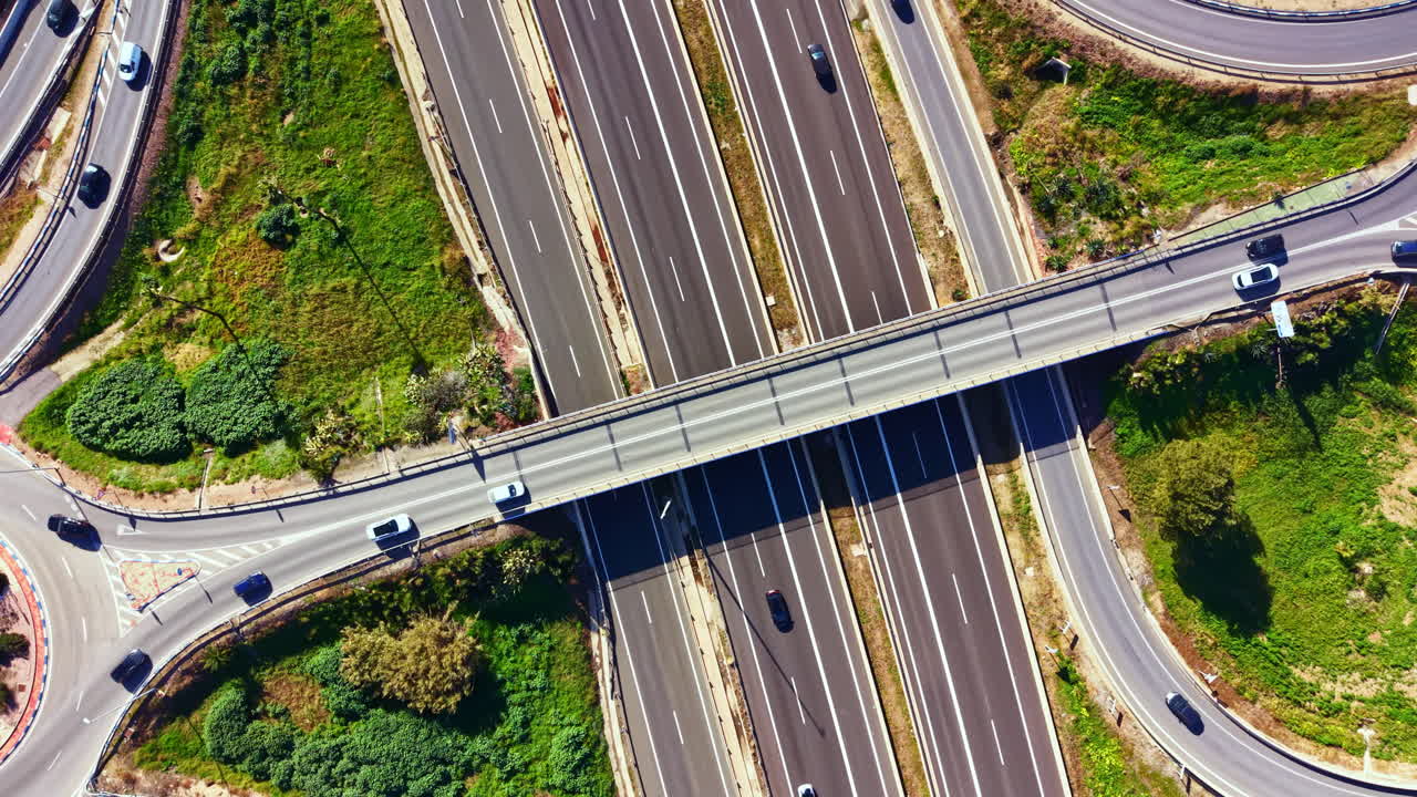 Trafficato svincolo autostradale che mostra diverse autostrade e cavalcavia, con veicoli in movimento, di giorno, in un'area suburbana.