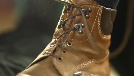 leather hiking boots being tied by a person while dust particles fly around in the bright morning sun light