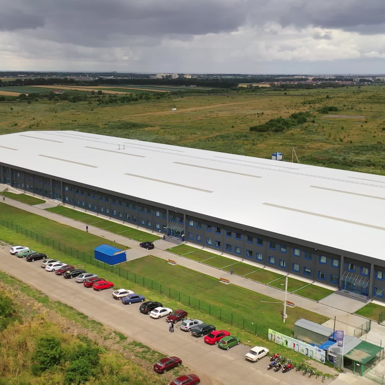 Exterior of newly built factory. View from the air on a modern manufacturing construction in the countryside in summer. Aerial view. Motion camera forward.