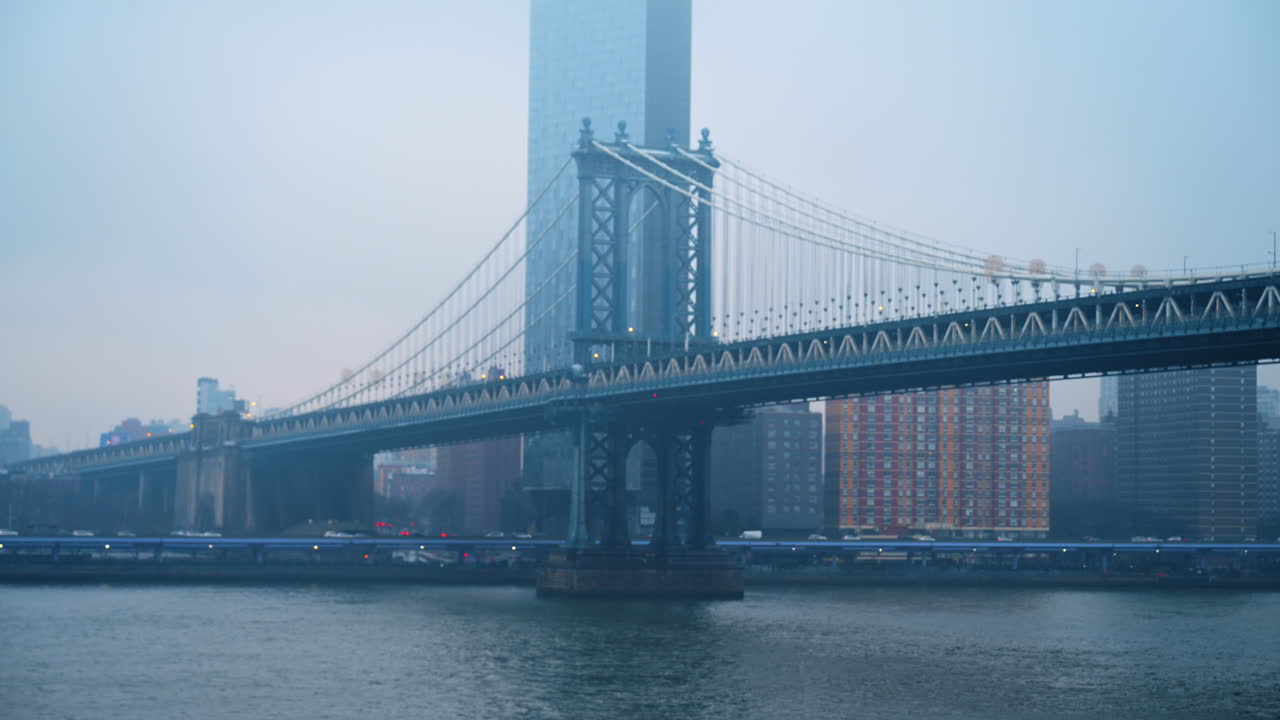 Ponte di Manhattan sul fiume East River con sfondo di grattacieli. Profilo laterale del Ponte di Manhattan che attraversa l'East River con un alto grattacielo moderno nella nebbia.
