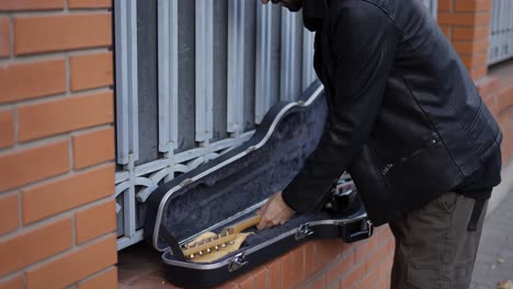 Man-puts-the-guitar-in-the-case