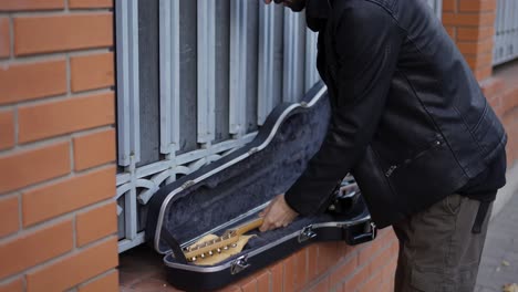 el hombre pone la guitarra en el estuche.