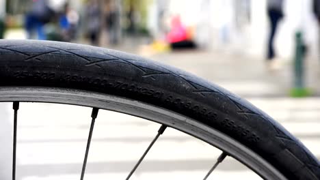 view of passers-by citizens and residents of the city through the spokes of a bicycle wheel