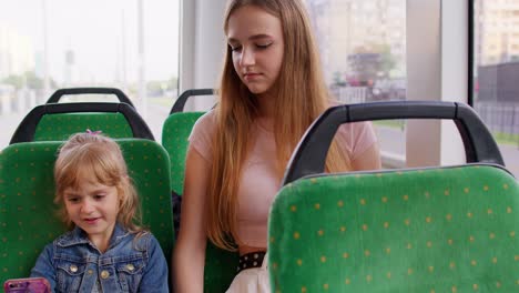 tired sleepy woman with daughter going home by bus and fall asleep, child kid girl use mobile phone