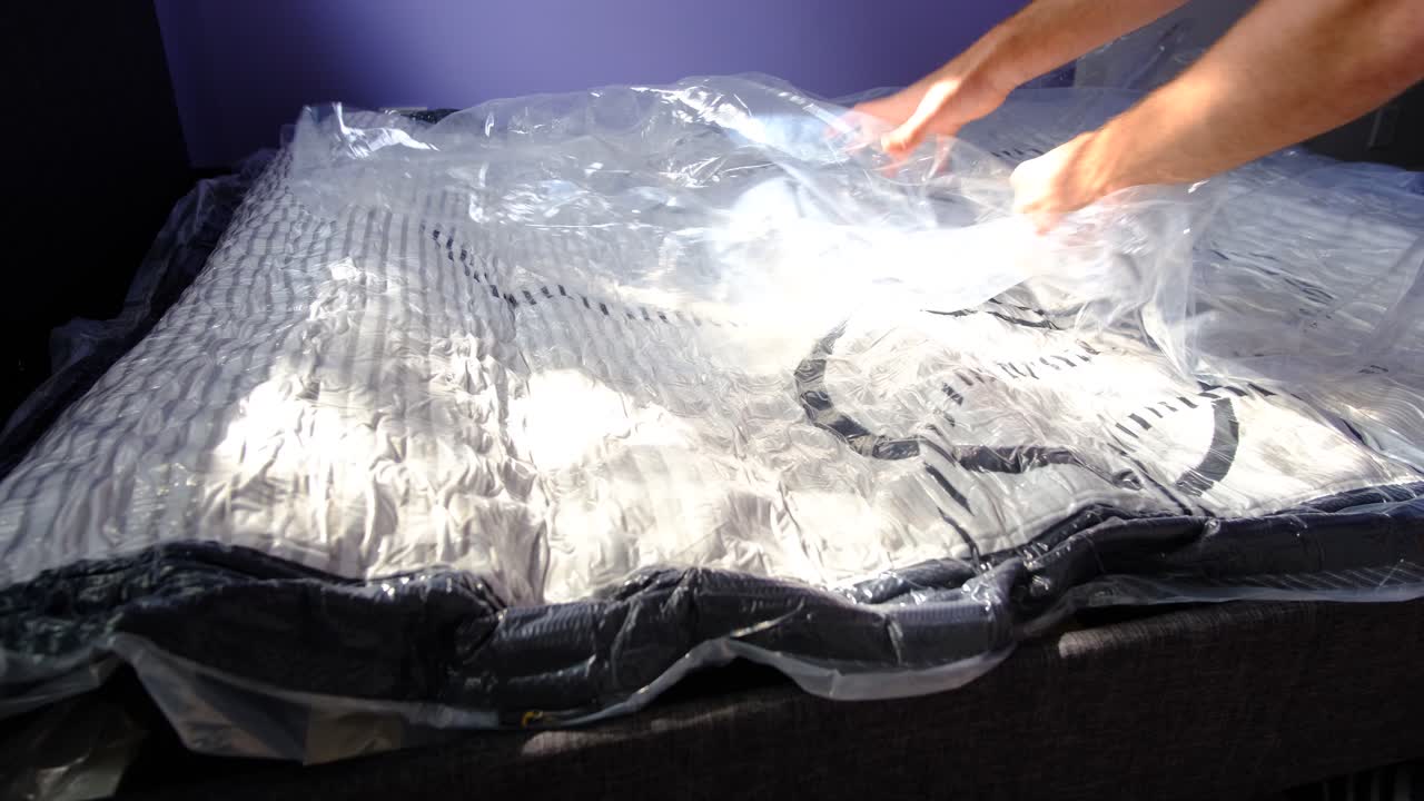 Unwrapping a flat packed mattress in a box