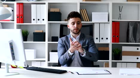businessman in gray jacket sitting at table in white office and signing, knocking and throwing sheet of paper