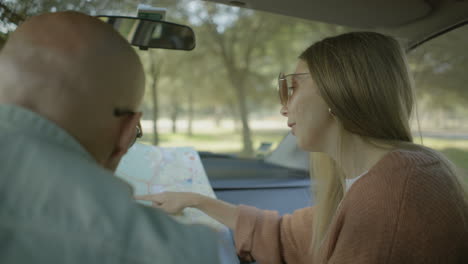 smiling couple looking at map in car