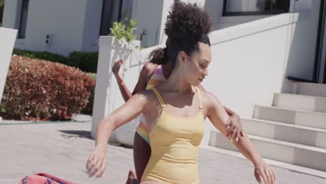 Happy-african-american-mother-and-daughter-applying-sunscreen-by-swimming-pool,-slow-motion