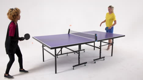 multiracial female table tennis players, serving and passing the ball on white background