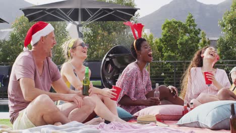 Happy-group-of-diverse-friends-playing-guitar-at-christmas-party-in-garden