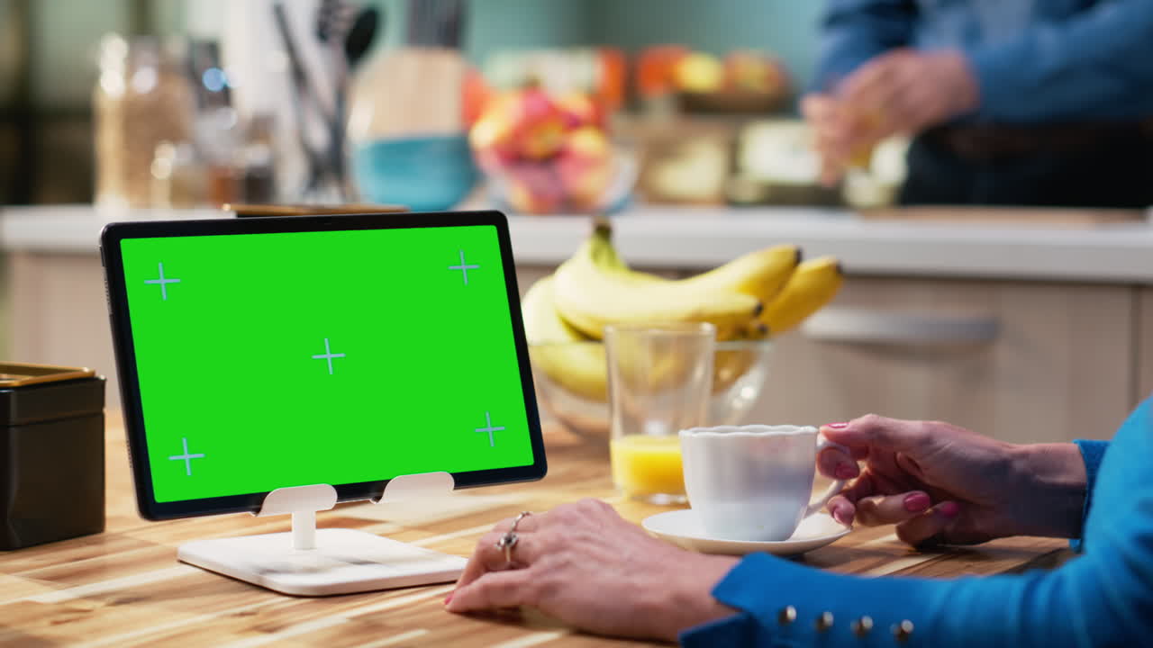 Isolated mockup tablet with old woman enjoying breakfast at kitchen table