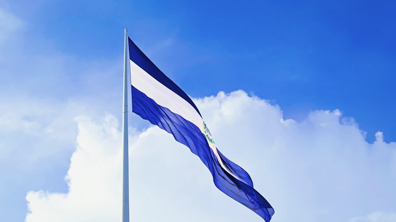 Primo piano della bandiera nazionale di El Salvador che sventola al vento durante una giornata di sole con nuvole sullo sfondo