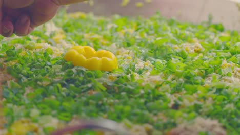 finishing a recipe adding pieces of pepper on top of cheese, rice and chicken and scallions