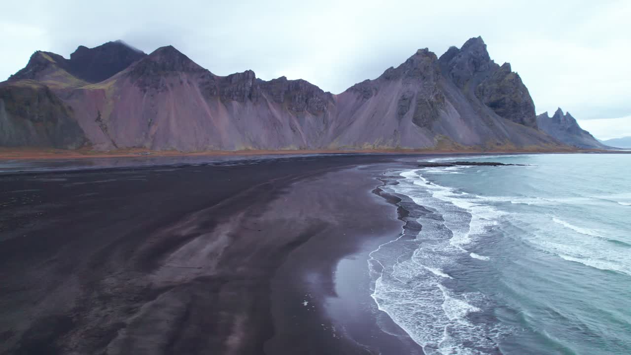 desde el aire: vestrahorn, con sus icónicos picos dentados y imponentes contrafuertes, se eleva dramáticamente desde esta oscura extensión como una colosal catedral de piedra